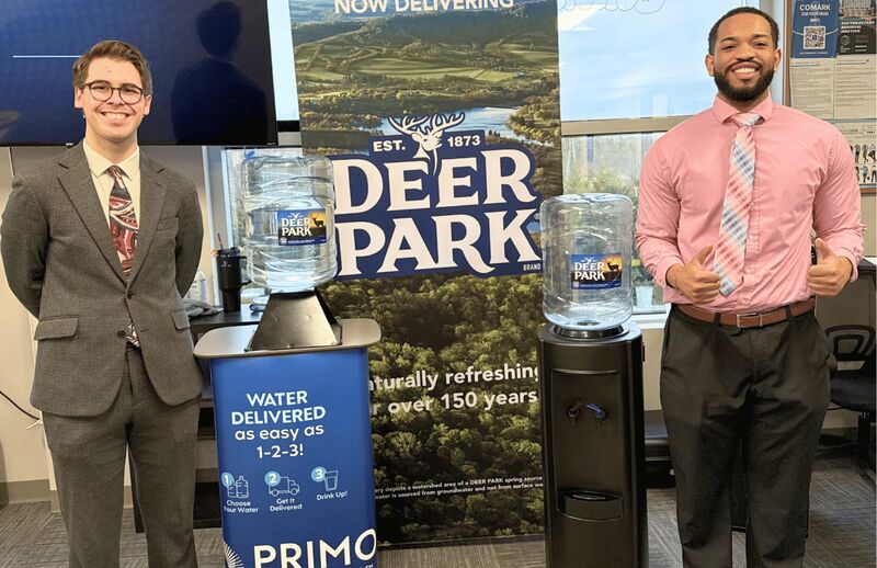 Two Palmora team members beside a client’s product display in the office