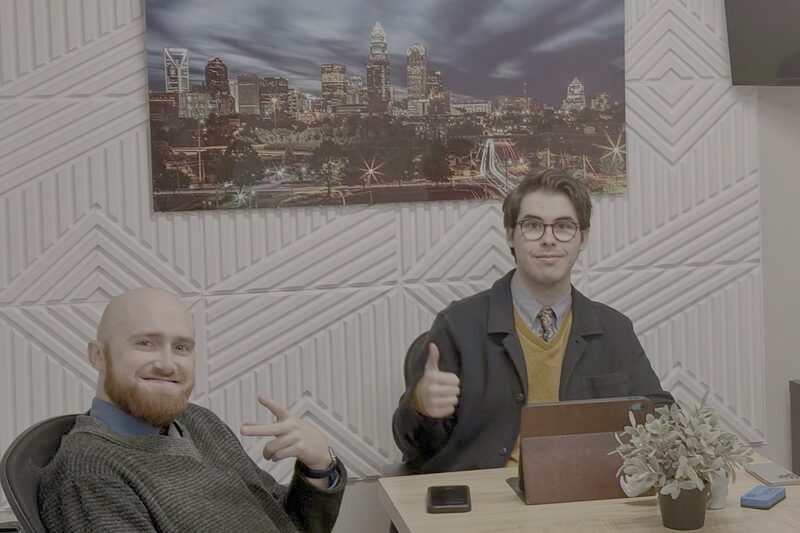 Two Palmora team members at a desk beneath a Charlotte skyline print