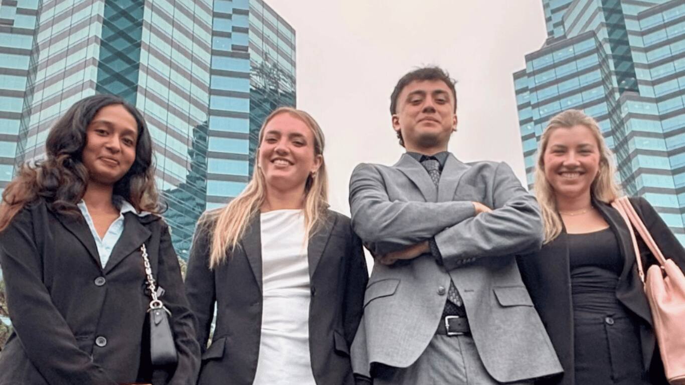 Four Palmora team members in business dress beneath Charlotte’s office towers