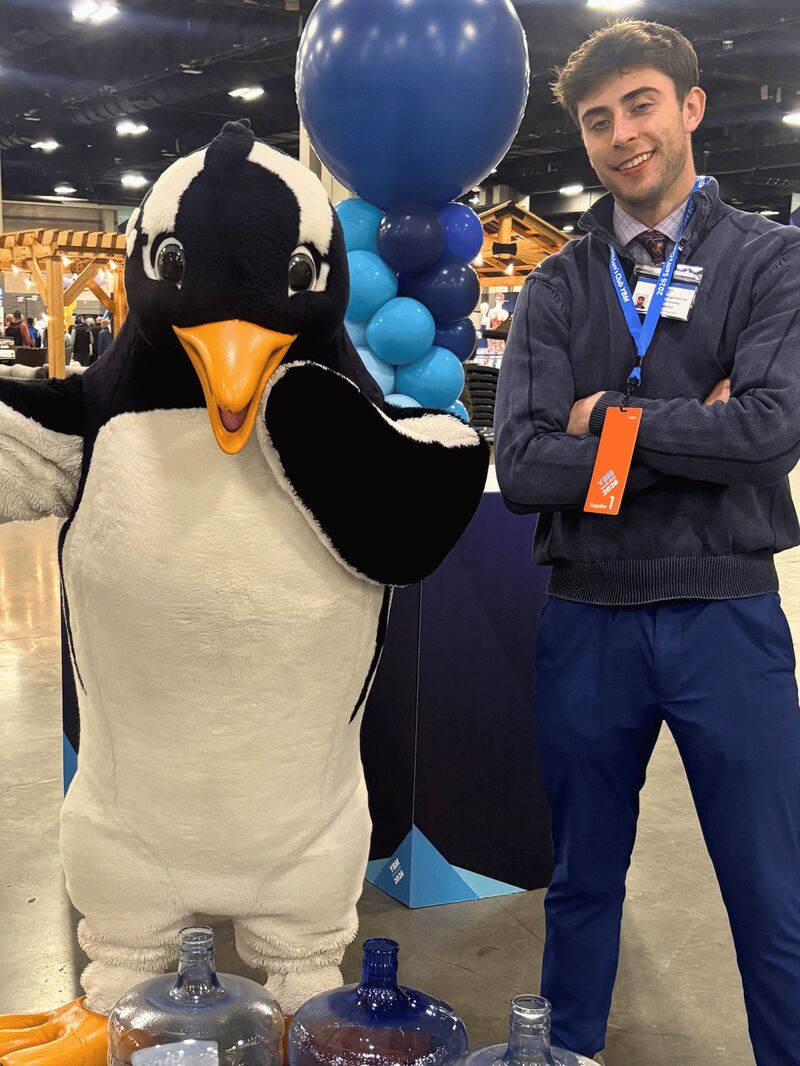 A Palmora team member with a brand mascot at a trade-show booth